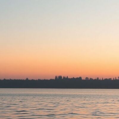 Silhouetted landscape with sunset and calm waters.