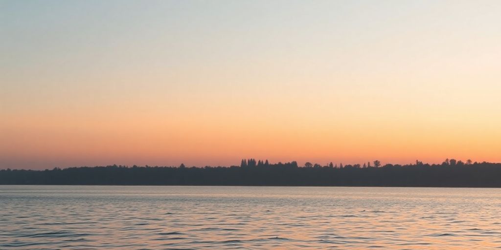 Silhouetted landscape with sunset and calm waters.