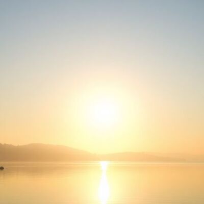 Tranquil sunrise over a peaceful lake and trees.