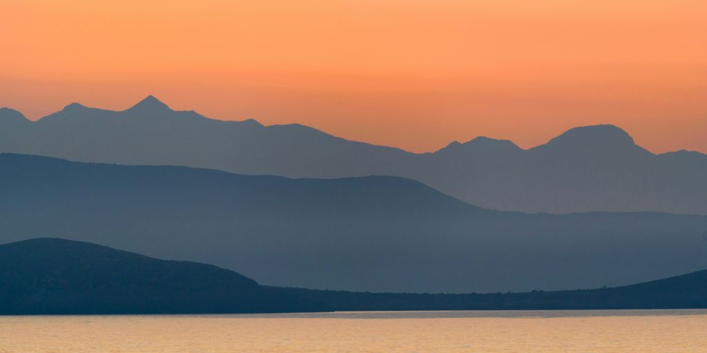 silhouette of mountains near body of water during golden hour