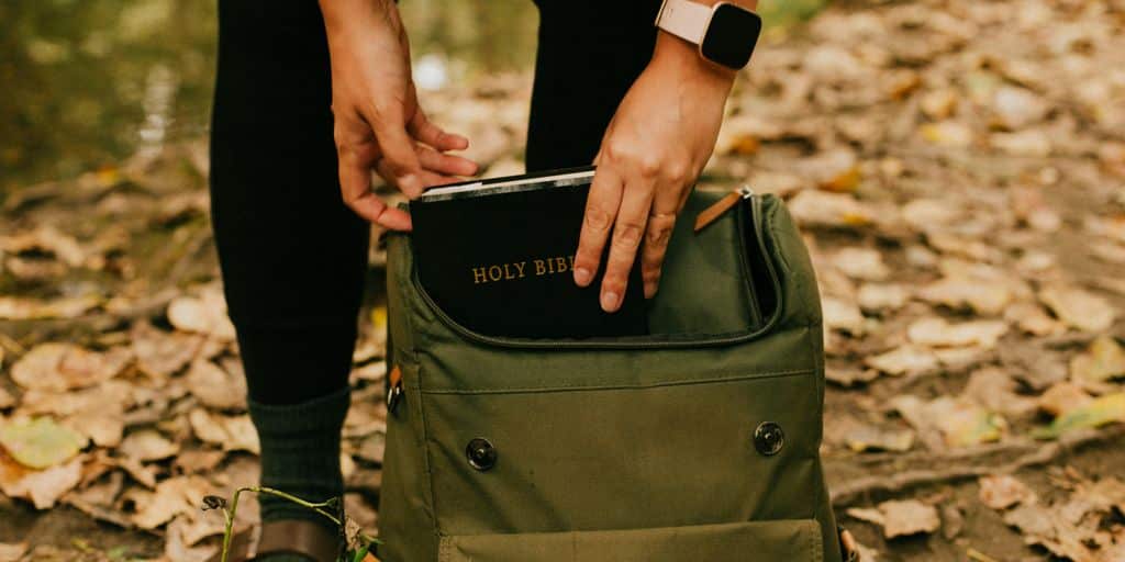 person holding green and black backpack