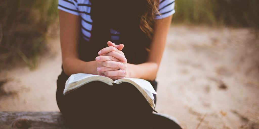 woman sitting on brown bench while reading book