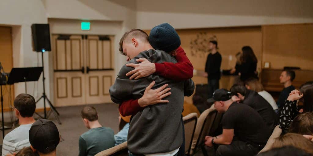 man in gray sweater carrying woman in black jacket