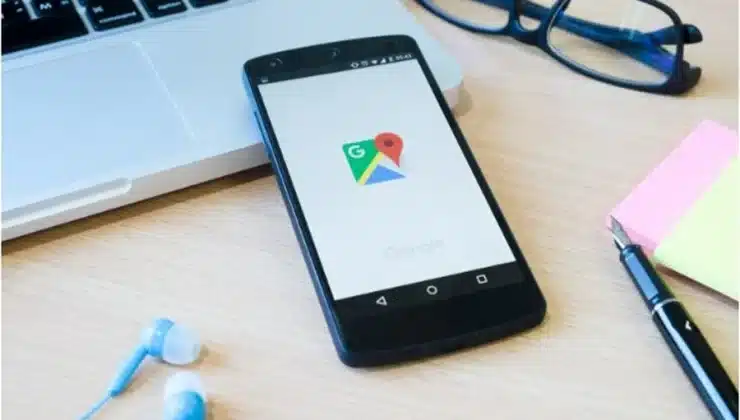 Smartphone displaying Google Maps on a desk with a laptop, glasses, and office supplies, representing local SEO and optimizing Google Business Profiles.